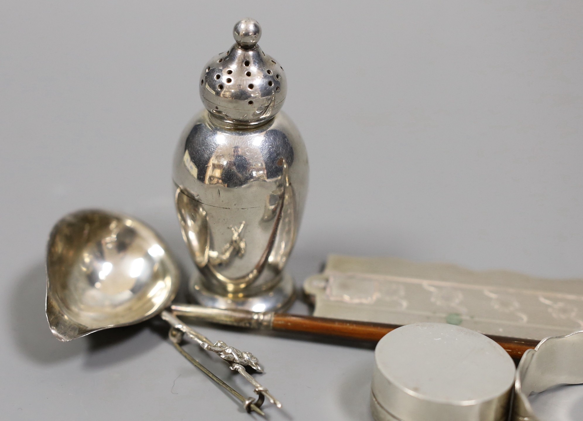A quantity of small silver or white metal items including a long handled server spoon, Chinese pepperette, pair of Victorian pepperettes, Victorian silver paten, 19th century toddy ladle by Taylor & Perry, folding comb,